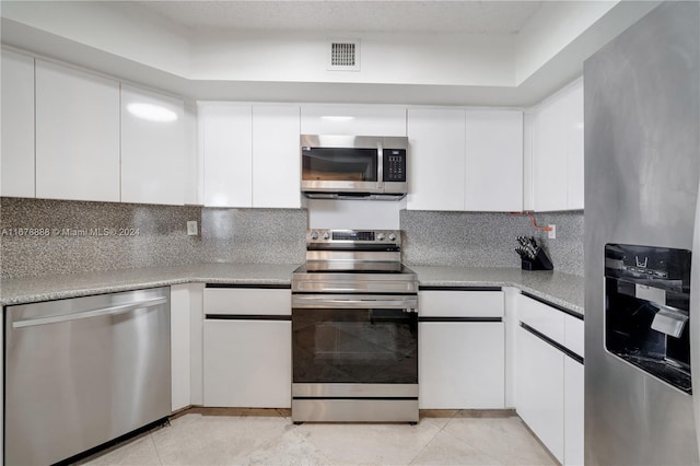 kitchen with white cabinetry, stainless steel appliances, and tasteful backsplash