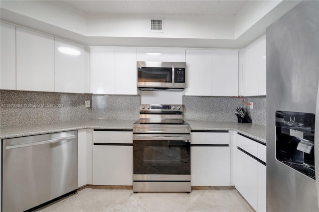6767 Collins Ave Unit 602, Miami Beach, FL 33141 - kitchen with stainless steel appliances, tasteful backsplash, white cabinetry, and light countertops