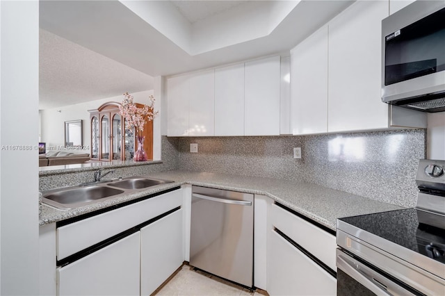 6767 Collins Ave Unit 602, Miami Beach, FL 33141 - kitchen featuring stainless steel appliances, a sink, white cabinets, decorative backsplash, and light countertops