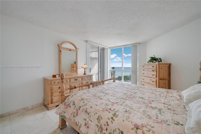 6767 Collins Ave Unit 602, Miami Beach, FL 33141 - bedroom featuring a water view, a wall of windows, and a textured ceiling