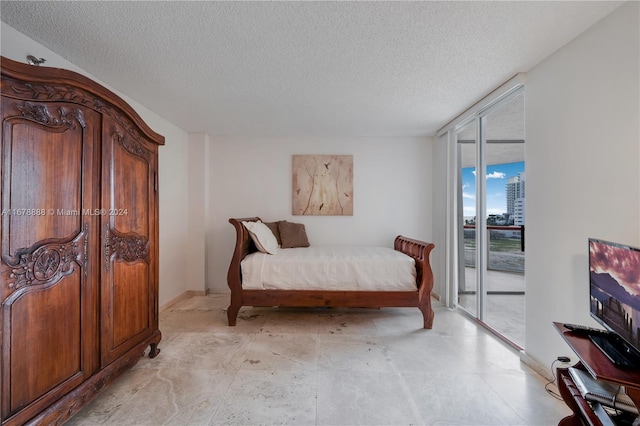 bedroom with a wall of windows, a textured ceiling, and access to exterior