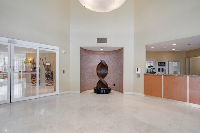 unfurnished living room featuring a towering ceiling