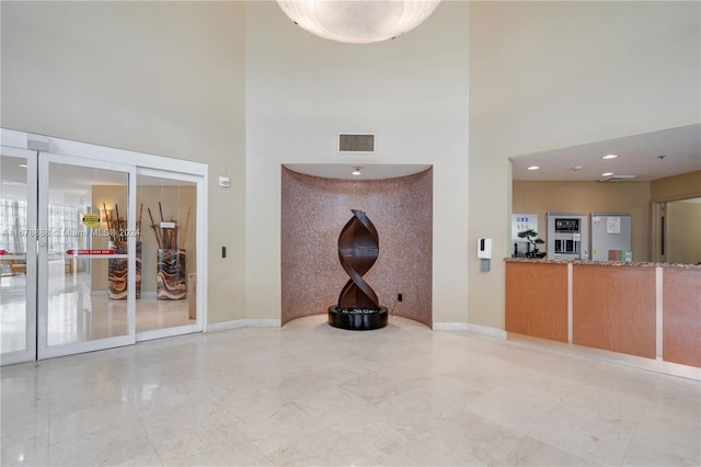 6767 Collins Ave Unit 602, Miami Beach, FL 33141 - unfurnished living room with a towering ceiling, french doors, and baseboards