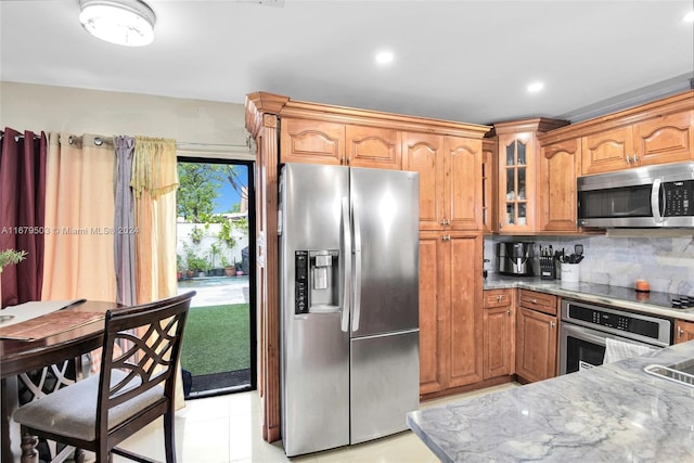 kitchen featuring light stone countertops, stainless steel appliances, light tile patterned flooring, and tasteful backsplash