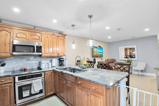 kitchen featuring kitchen peninsula, tasteful backsplash, appliances with stainless steel finishes, pendant lighting, and sink