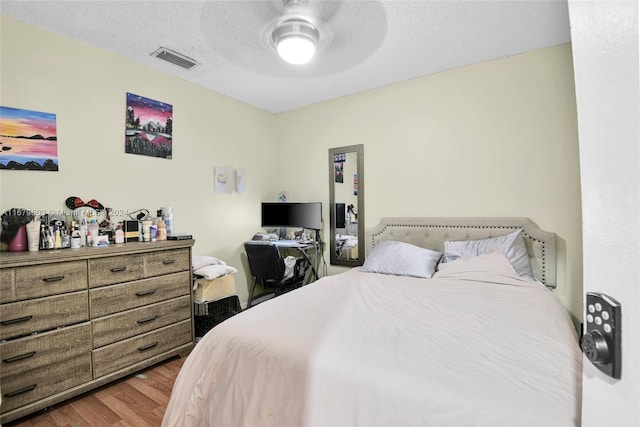 bedroom with hardwood / wood-style floors, a textured ceiling, and ceiling fan