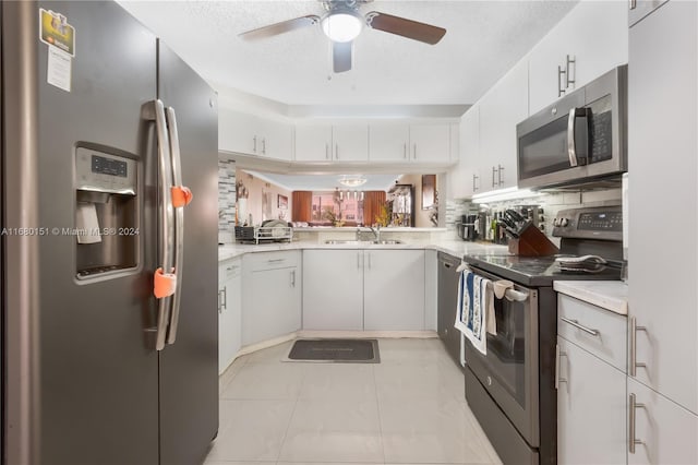 kitchen featuring a textured ceiling, white cabinetry, stainless steel appliances, decorative backsplash, and light tile patterned floors