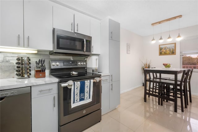 kitchen with tasteful backsplash, light tile patterned floors, white cabinetry, pendant lighting, and stainless steel appliances