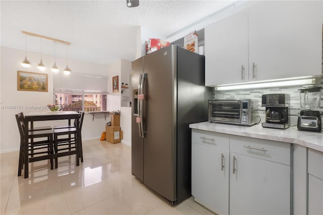 kitchen with decorative backsplash, stainless steel fridge, light tile patterned floors, a textured ceiling, and pendant lighting