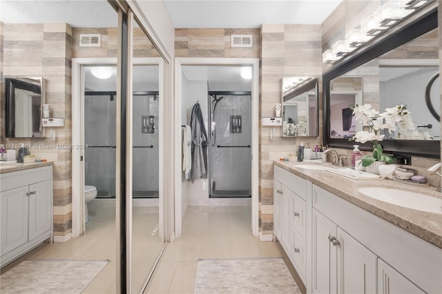 bathroom with a textured ceiling, walk in shower, toilet, vanity, and tile patterned floors