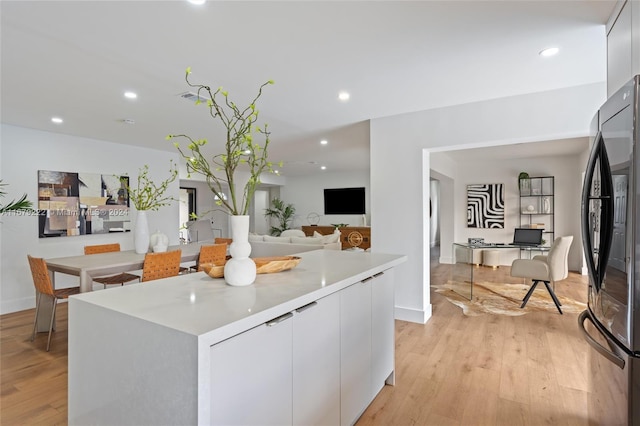 kitchen with light hardwood / wood-style floors, fridge, white cabinetry, and a center island