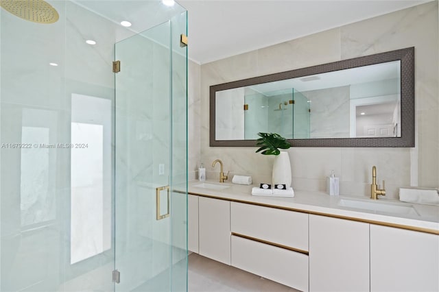 bathroom with a shower with door, vanity, and tile walls