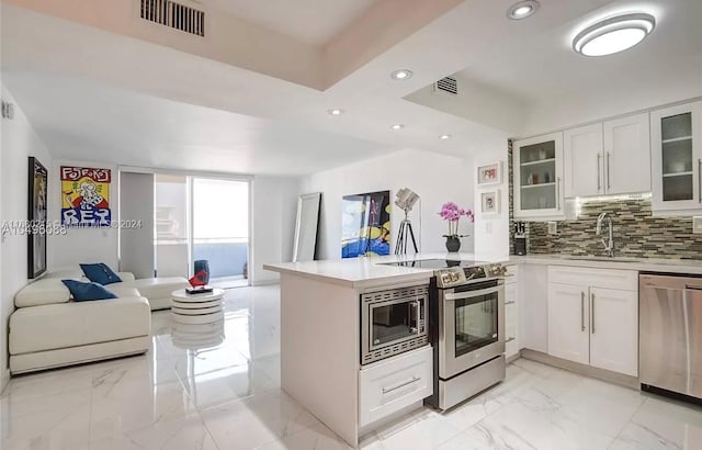 kitchen featuring kitchen peninsula, white cabinetry, stainless steel appliances, and backsplash