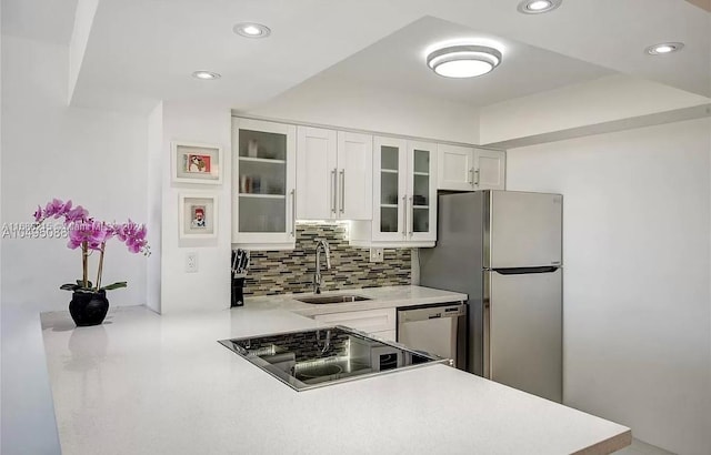 kitchen featuring appliances with stainless steel finishes, sink, kitchen peninsula, white cabinets, and decorative backsplash