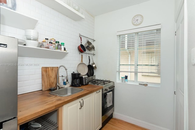 kitchen featuring wooden counters, sink, backsplash, and gas range