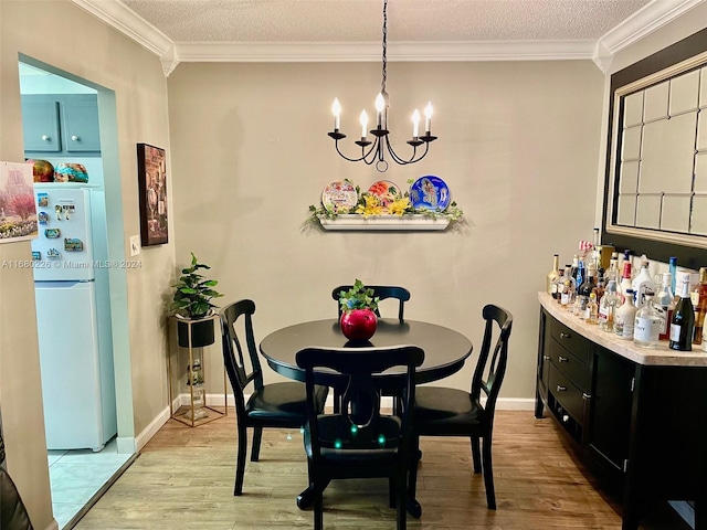 dining area with light hardwood / wood-style floors, ornamental molding, and a textured ceiling