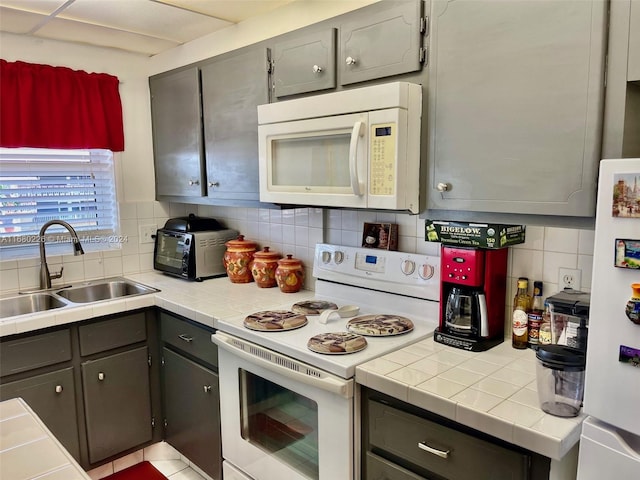 kitchen with gray cabinets, sink, decorative backsplash, and white appliances