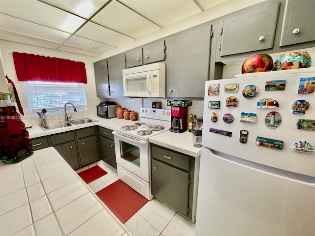 kitchen featuring sink, decorative backsplash, tile counters, and white appliances