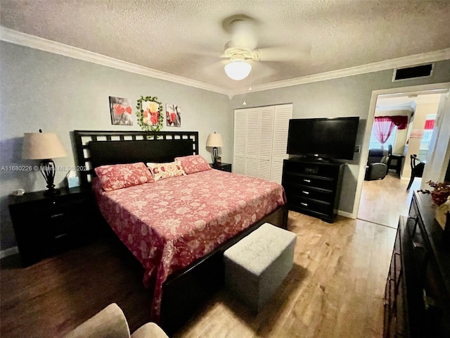 bedroom featuring a closet, crown molding, a textured ceiling, light hardwood / wood-style floors, and ceiling fan