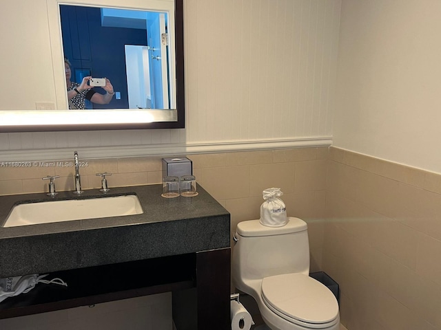 bathroom featuring vanity, toilet, and tile walls