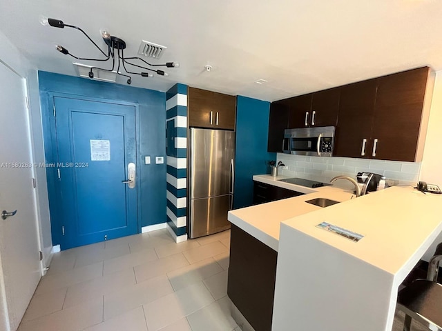 kitchen featuring appliances with stainless steel finishes, sink, kitchen peninsula, decorative backsplash, and a breakfast bar area