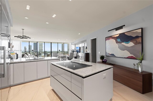 kitchen featuring black electric stovetop, ceiling fan, light tile patterned floors, a kitchen island, and white cabinetry