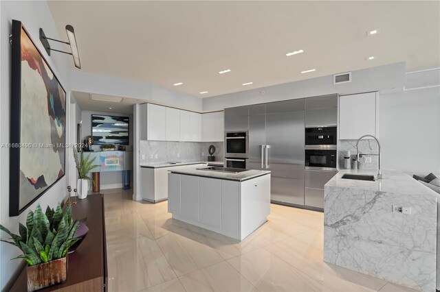 kitchen featuring white cabinets, sink, decorative backsplash, appliances with stainless steel finishes, and a kitchen island