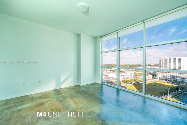 empty room with concrete floors and a wall of windows