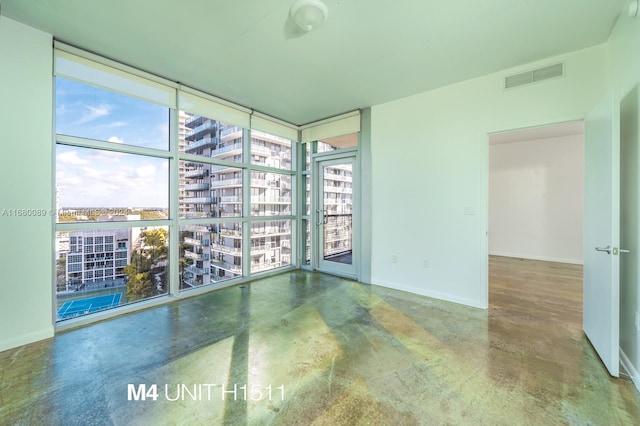 empty room with concrete floors, a healthy amount of sunlight, and floor to ceiling windows