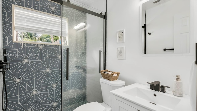 bathroom featuring vanity, toilet, and a shower with shower door