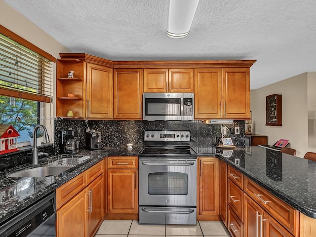 kitchen featuring appliances with stainless steel finishes, sink, dark stone countertops, decorative backsplash, and light tile patterned floors