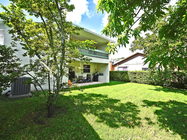 rear view of property with a balcony, central AC, and a yard