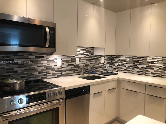 kitchen with sink, decorative backsplash, white cabinetry, and stainless steel appliances