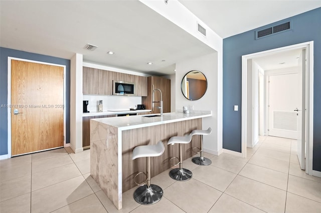 401 N Birch Rd Unit 505, Fort Lauderdale, FL 33304 - kitchen with built in microwave, modern cabinets, a sink, a breakfast bar, and a peninsula
