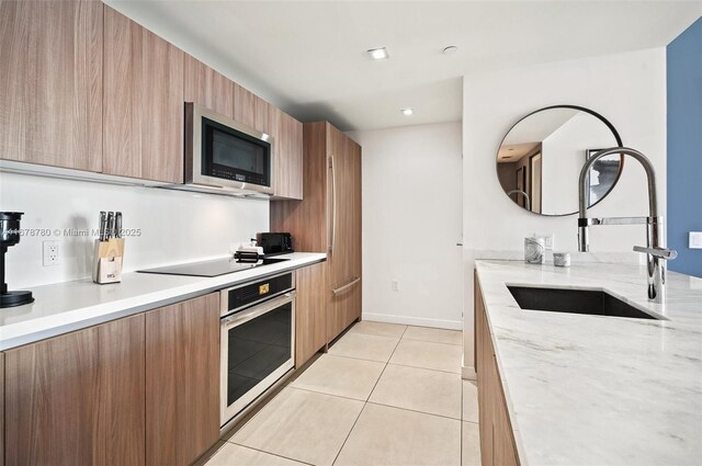 401 N Birch Rd Unit 505, Fort Lauderdale, FL 33304 - kitchen featuring stainless steel appliances, a sink, modern cabinets, light tile patterned floors, and light stone countertops