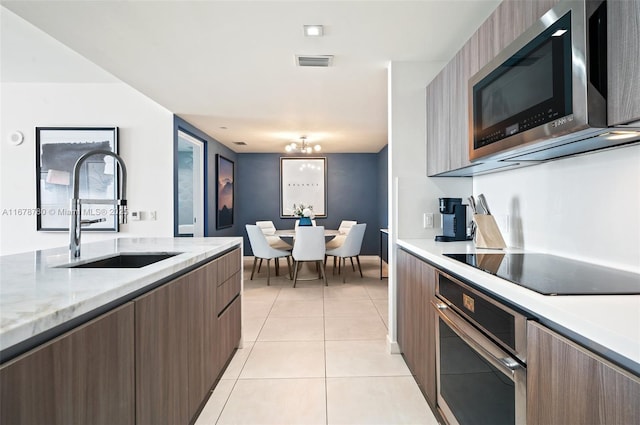 401 N Birch Rd Unit 505, Fort Lauderdale, FL 33304 - kitchen with appliances with stainless steel finishes, a sink, modern cabinets, light tile patterned floors, and a chandelier