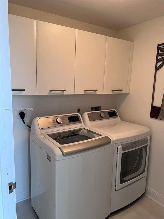 clothes washing area featuring cabinet space, baseboards, and washing machine and dryer