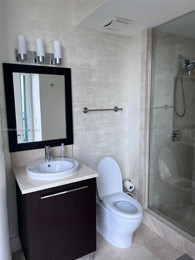 bathroom with vanity, a shower with shower door, toilet, and tile patterned flooring