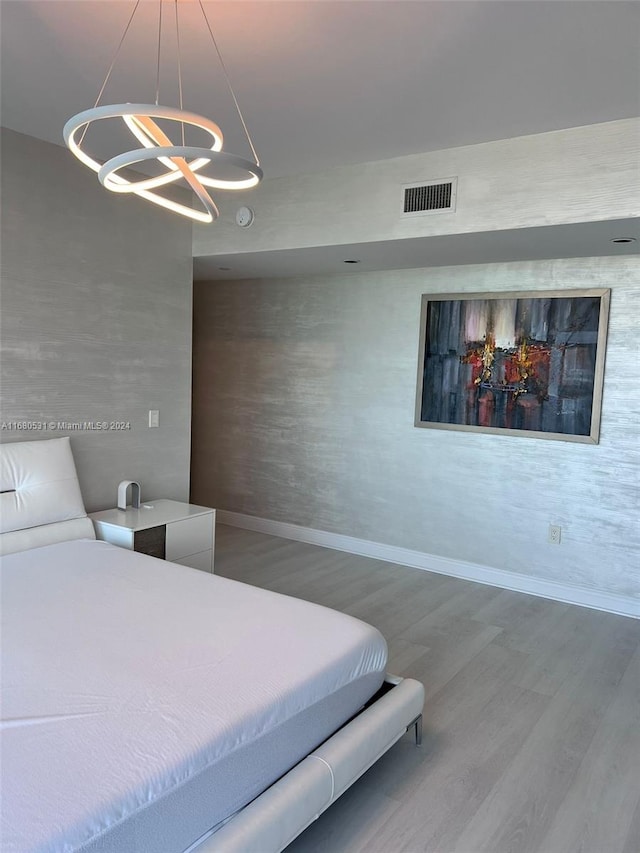 bedroom featuring a notable chandelier, baseboards, visible vents, and wood finished floors