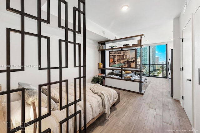 bedroom with stainless steel fridge, hardwood / wood-style floors, and floor to ceiling windows