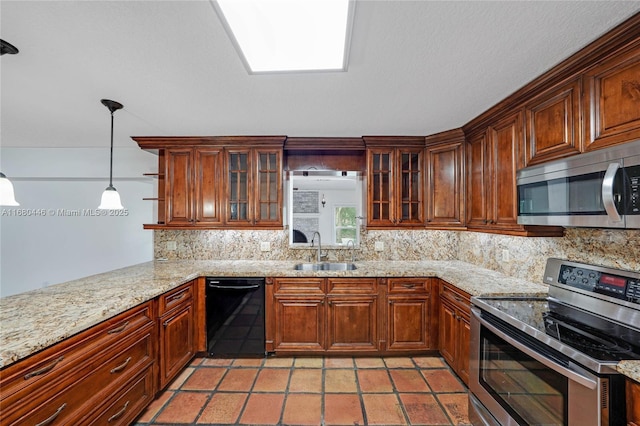 kitchen with kitchen peninsula, light stone countertops, stainless steel appliances, sink, and decorative light fixtures