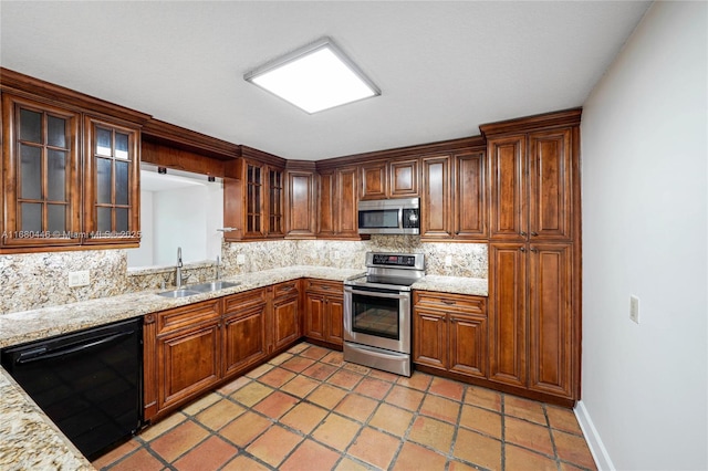 kitchen with decorative backsplash, light stone counters, sink, and appliances with stainless steel finishes