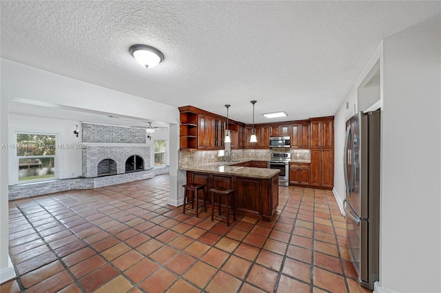 kitchen featuring decorative backsplash, appliances with stainless steel finishes, kitchen peninsula, a breakfast bar, and hanging light fixtures