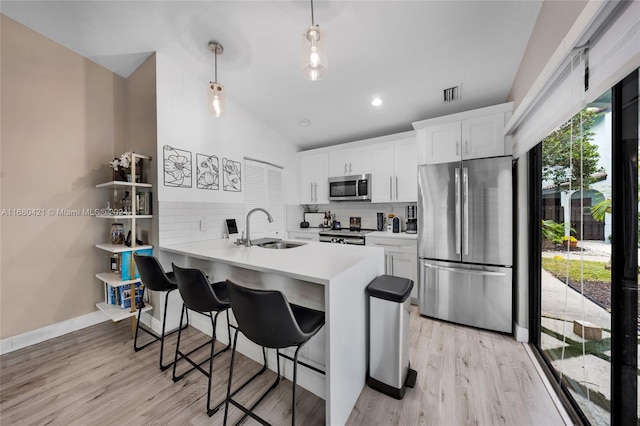 kitchen featuring white cabinetry, appliances with stainless steel finishes, kitchen peninsula, and decorative backsplash