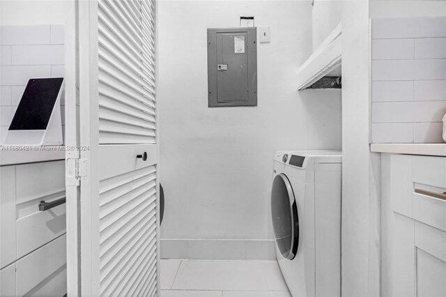 clothes washing area featuring electric panel, light tile patterned flooring, and washer / clothes dryer