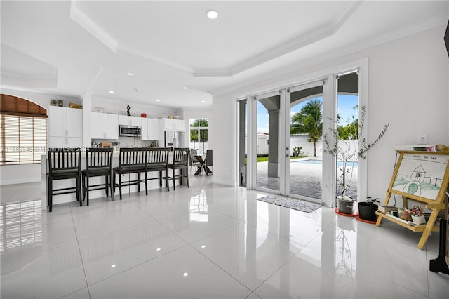 tiled dining area featuring ornamental molding and a tray ceiling