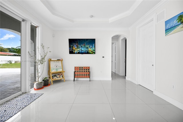 interior space with crown molding, a tray ceiling, and light tile patterned floors