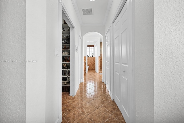 hall featuring dark tile patterned floors and crown molding