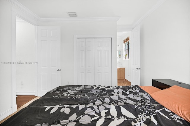 bedroom featuring a closet, hardwood / wood-style flooring, and crown molding