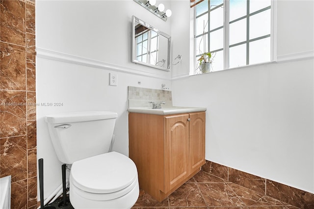 bathroom with tile walls, vanity, and toilet